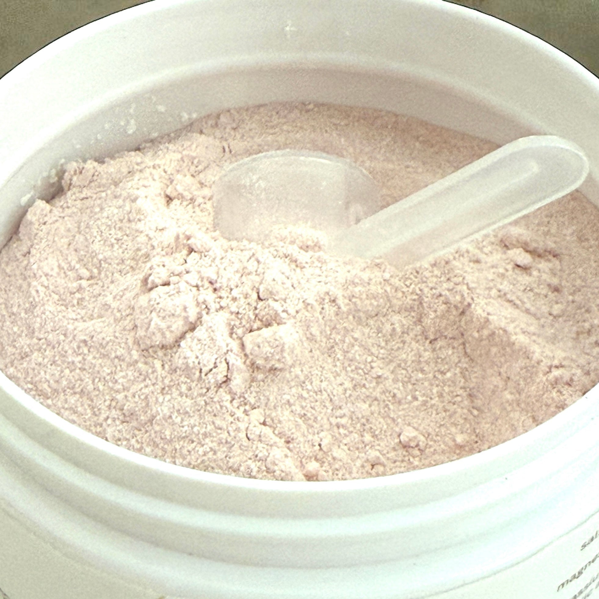 Container of Lionlyte drink mix with a spoon inside on a gray background